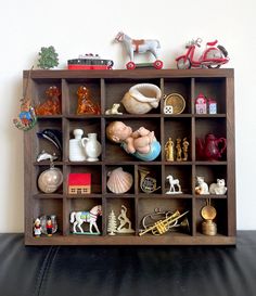 a shelf filled with figurines and toys on top of a black leather couch