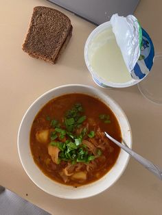 a bowl of soup next to a slice of bread