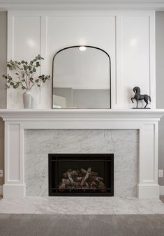 a white fireplace with a mirror above it