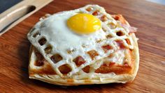 a waffle with an egg on top is sitting on a cutting board next to a knife