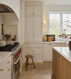 a kitchen with white cabinets and wood flooring next to a stove top oven, counter tops and drawers