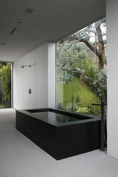 an instagramted photo of a bathtub in the middle of a room with glass walls