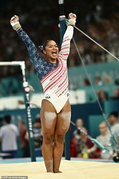 a woman is holding her hands up in the air while standing on a balance beam