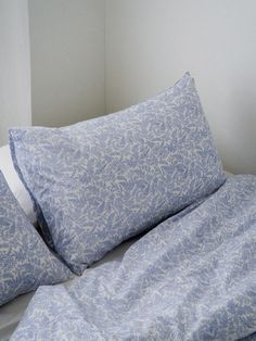 a bed with blue sheets and pillows on top of it in a white walled room