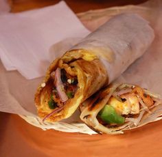 two burritos sitting on top of a brown plate