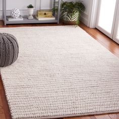 a white rug on the floor next to a potted plant