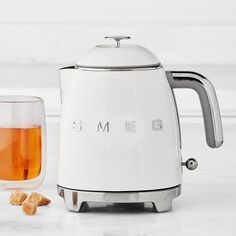 a white toaster sitting next to a glass filled with liquid and some cookies on the table