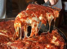 a person taking a slice of deep dish pizza