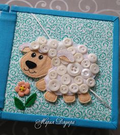 a sheep made out of buttons sitting on top of a piece of fabric with a flower