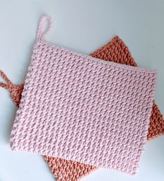 two crocheted pink and orange squares sitting next to each other on a white surface