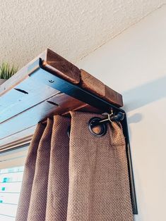 a curtain is hanging on the side of a window in front of a potted plant