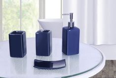 three pieces of bathroom accessories on a glass table in front of a white curtained window