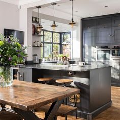 a kitchen with an island and wooden table in front of the stove top ovens