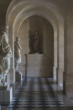 some statues are standing in the middle of a room with checkered tile flooring