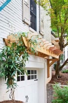 a white house with a tree in the front yard and an awning over it