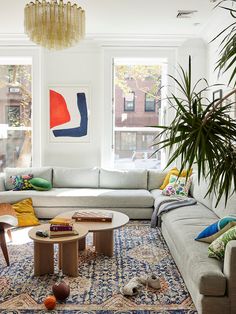 a living room filled with lots of furniture and plants on the floor next to large windows