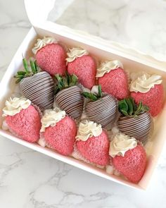 a box filled with strawberries on top of a marble countertop covered in white frosting