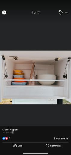 an open refrigerator door with bowls and plates in the bottom shelf, on top of it