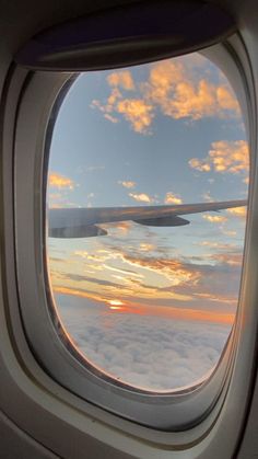 an airplane window with the view of clouds and sunset in the sky as seen from inside