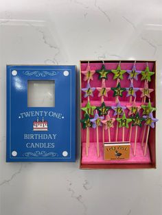 an open box with candles in it next to a pink and blue box that says twenty one birthday candles