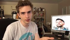 a young man sitting in front of a computer screen with the words hey bows on it