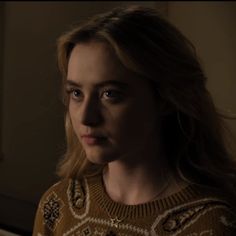 a woman in a sweater looking at the camera with an intense look on her face