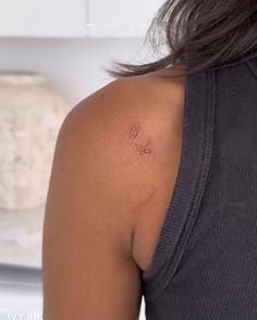 the back of a woman's shoulder with a small tattoo on her left arm