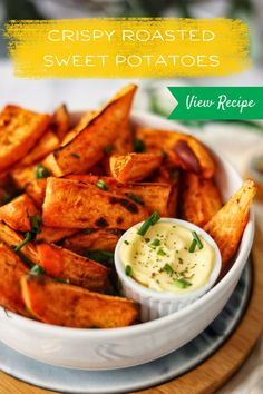 crispy roasted sweet potatoes in a white bowl with ranch dressing on the side and text overlay that reads, crispy roasted sweet potatoes