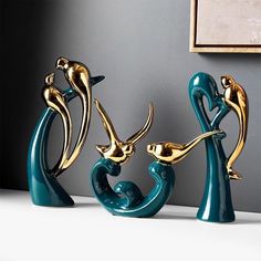 three gold and blue sculptures on a white table