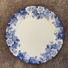 a blue and white plate sitting on top of a carpeted floor next to a wall