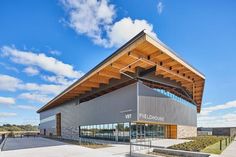 the exterior of a large building with a wooden roof and glass windows on it's sides