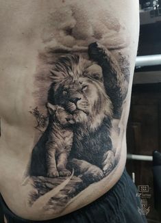 a man with a lion tattoo on his stomach holding a baby tiger in front of him