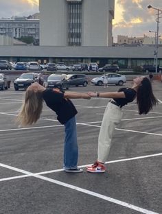 two girls are holding hands in an empty parking lot