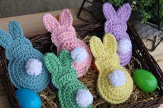 four crocheted easter bunnies sitting in a basket on top of a table