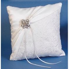 a white pillow with a bow on the side and a brooch in the middle