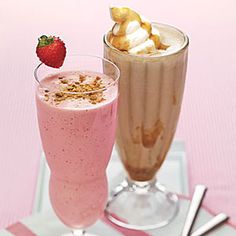 two glasses filled with different types of food on top of a pink and white table