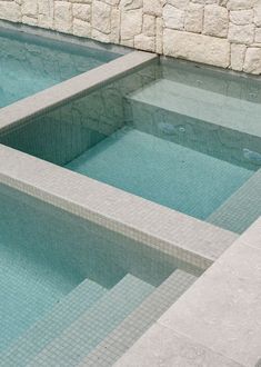 an empty swimming pool with steps leading up to the water and stone wall behind it