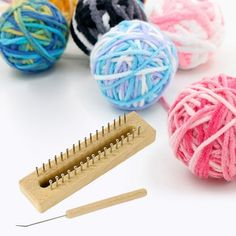 several balls of yarn are next to a knitting needle and a wooden skeine