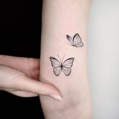 a woman's arm with two small butterflies on the left side of her arm