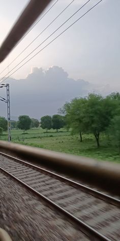 a train traveling down tracks next to a lush green field with trees in the distance