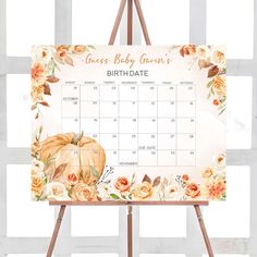 an easel with a baby shower calendar on it and flowers around the frame, in front of a white background