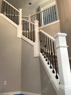 a staircase with black railings and white balconies in a home under construction