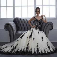 a woman in a black and white ball gown sitting on a gray couch next to a window