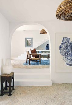 an arched doorway leads to a dining room and living room with blue rugs on the floor