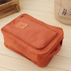 an orange bag sitting on top of a wooden floor next to a brown bag and other items