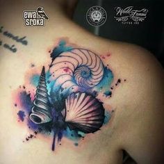 the back of a woman's shoulder with an abstract tattoo design and seashell on it