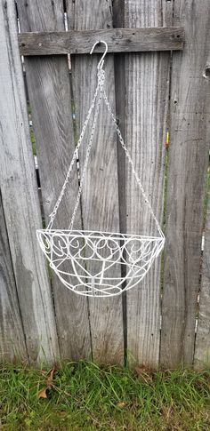 a white wire hanging basket on a wooden fence