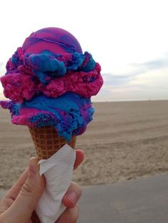 someone holding up an ice cream cone with blue and red toppings