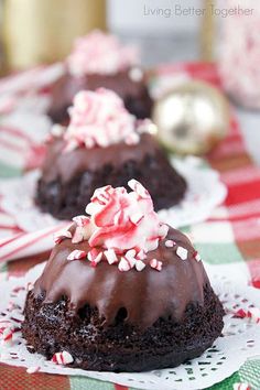 two chocolate cupcakes with peppermint on top, sitting on paper doily