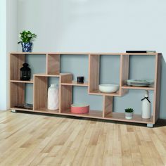 a wooden shelf with some plates and bowls on it in a room that has hardwood floors